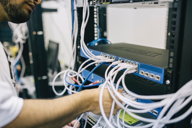 Photo of a network technician confectioning patch cables to an ethernet switch